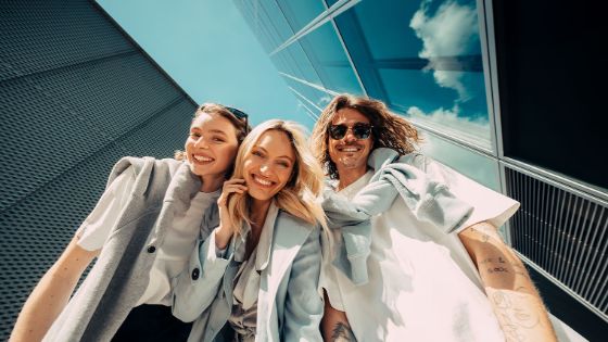 Drei junge Erwachsene laufen froh und frei gemeinsam durch die Stadt und nutzen ihre Cashback Cards