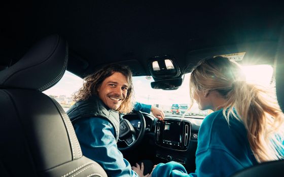 Cashback Cards - Junges Paar sitzt im Mietauto während einer Reise 